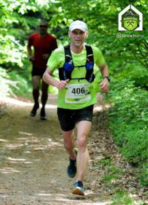 Biegacz na ścieżce w lesie w białej czapeczce żółtej podkoszulce i spodenkach